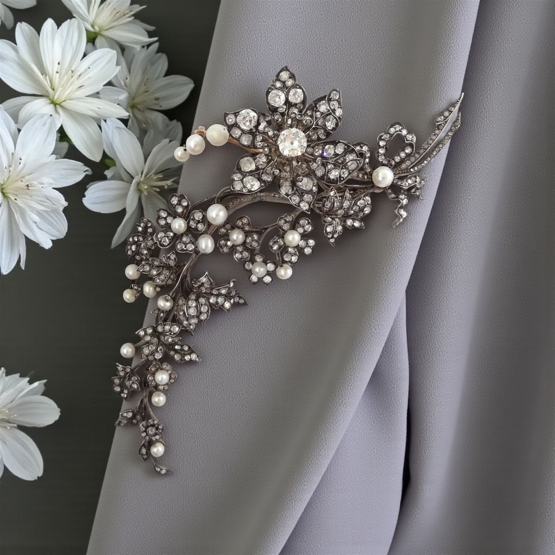 19th century gold and silver diamond and pearl en tremblant detachable brooch, the flower tremblant with a principal old cut diamond of approx 1.90 carat, the petals and stamen set with old cut and rose cut diamonds, total diamond weight approx 9.10 carat, to a foliate spray set set with further rose cut diamond and white / pink / cream pearls and ribbon tie