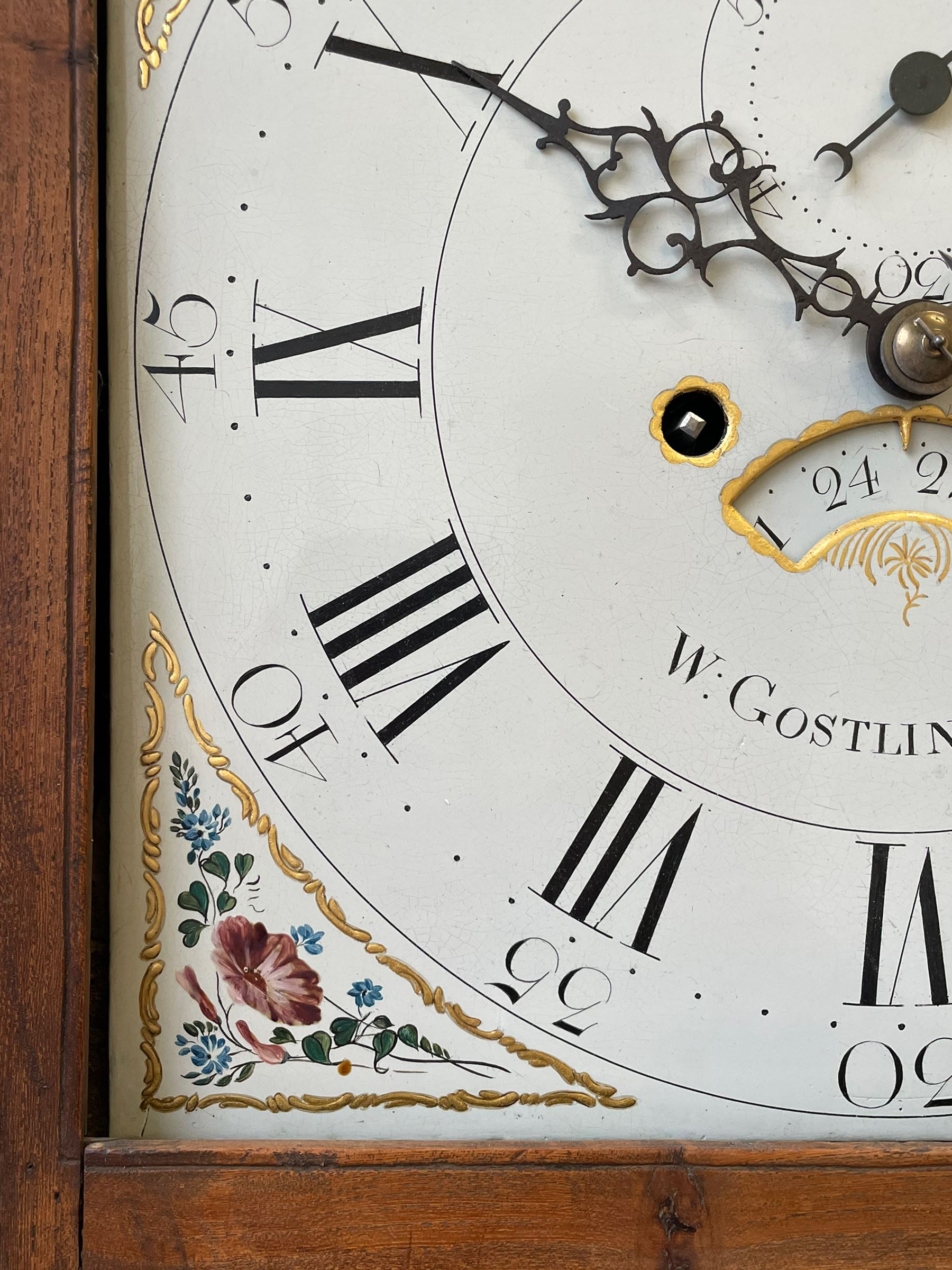 William Gostling of Diss  (Norfolk)-  Late 18th century 8-day oak longcase clock c1780-90, break arch top with scalloped cresting and three brass finials, glazed break arch hood door flanked by turned pilasters with brass capitals, trunk with a long trunk door and rounded top on a square plinth with an applied and shaped skirting, early painted Wilson of Birmingham dial with Roman numerals and five minute Arabic's, matching steel hands and second pointer, arched square ended calendar aperture with date disc behind, floral spandrels within gesso borders and a painted rocking automaton representing Mercury to the break arch, dial pinned via a false plate to a weight driven rack striking movement with a recoil anchor escapement, striking the hours on a cast bell. With pendulum weights and key. 
William Gostling (II) is recorded as working in Diss from 1774 to 1797, succeeded by widow Anne and son George . The dial of this clock is illustrated and discussed in detail in M.F. Tennants book 
