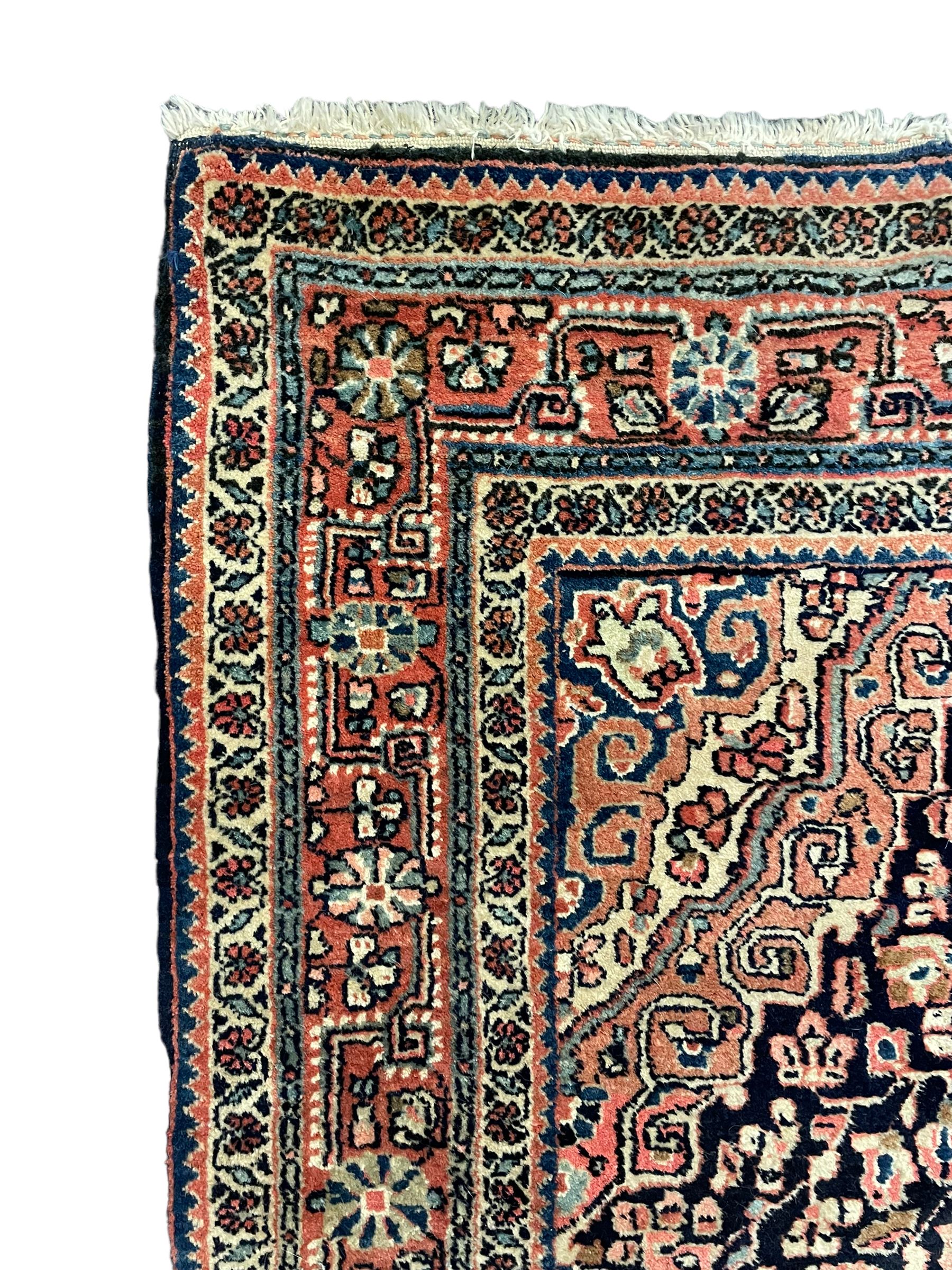 Persian indigo ground rug, the field decorated with intricate interlaced foliage branches and small flower heads, shaped floral design central medallion, the border decorated with scrolling branch and flower heads within guard bands 