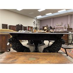 Large 19th century carved oak library table, the rectangular top with lunette carved edge over cartouche panelled and carved  scroll frieze, the central tapering rectangular support relief carved with masks and garlands, on four carved seated lion supports at each corner, on flat angular stretcher with recessed castors stamped ‘Bartholomew & Fletcher, London’