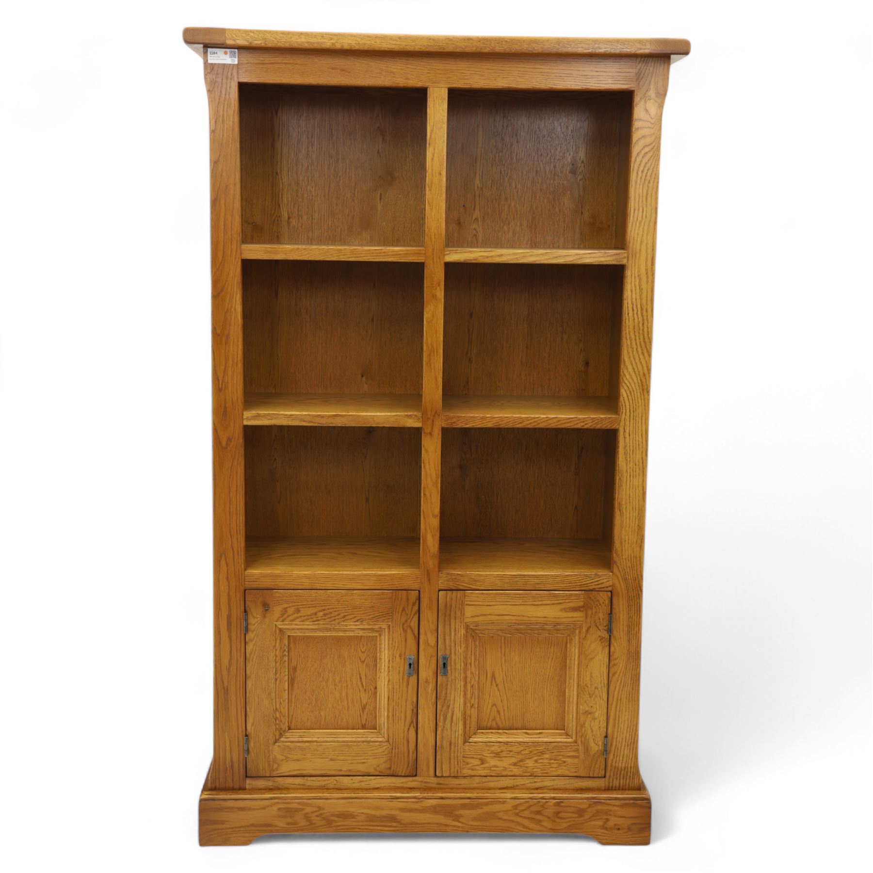 Old Charm - 'Chatsworth' light oak bookcase with two cupboards, featuring two fixed horizontal shelves forming six  rectangular open compartments, over twin panelled cupboard doors, chamfered uprights and plinth base