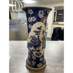 Late 19th century Chinese blue and white gu beaker vase, decorated with two lobed reserves containing precious objects, against a prunus and cracked ice ground, with apocryphal Kangxi mark beneath, H30.5cm