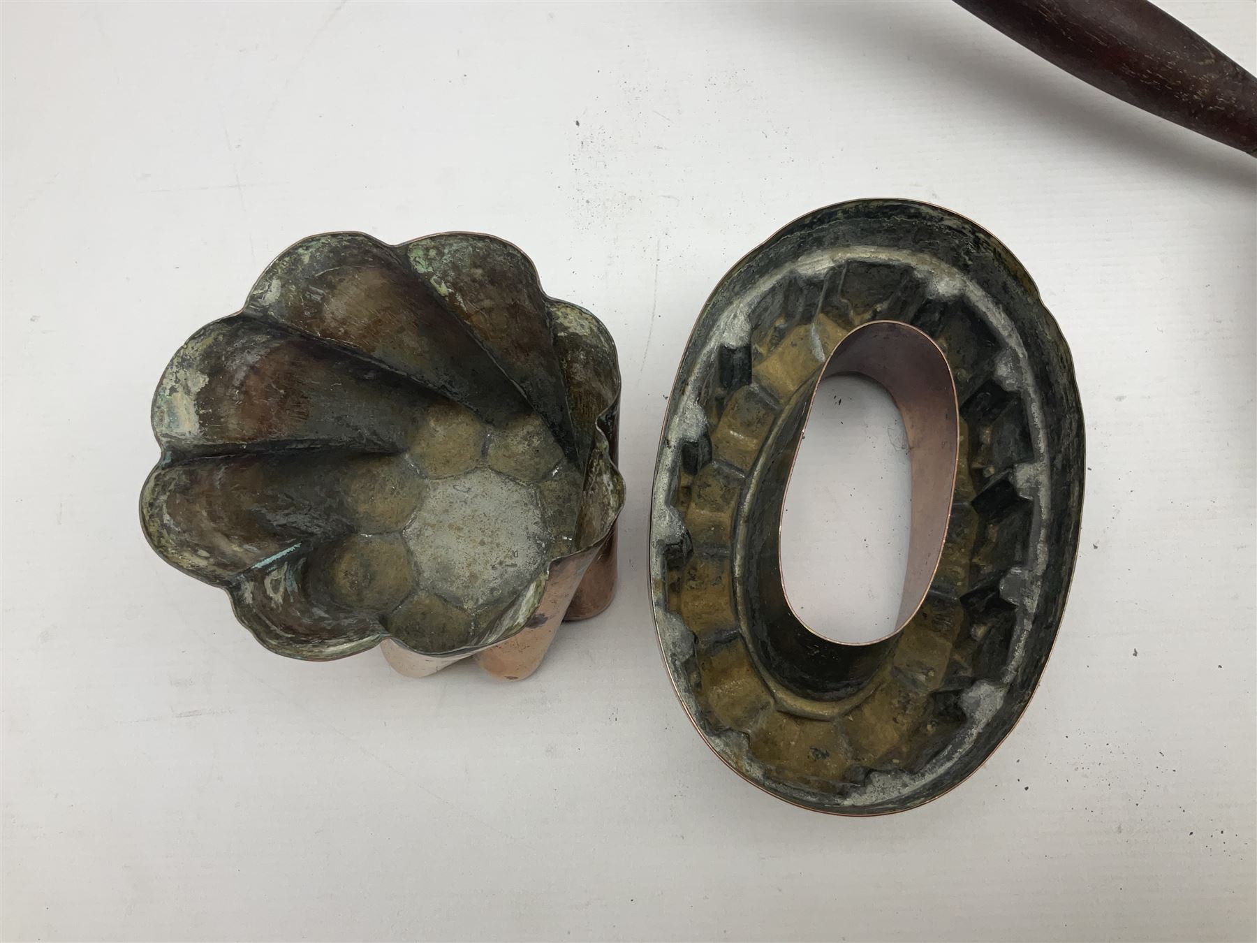 Four Victorian copper moulds, together with a graduating set of copper pans with wooden handles and finials to covers, largest pan 