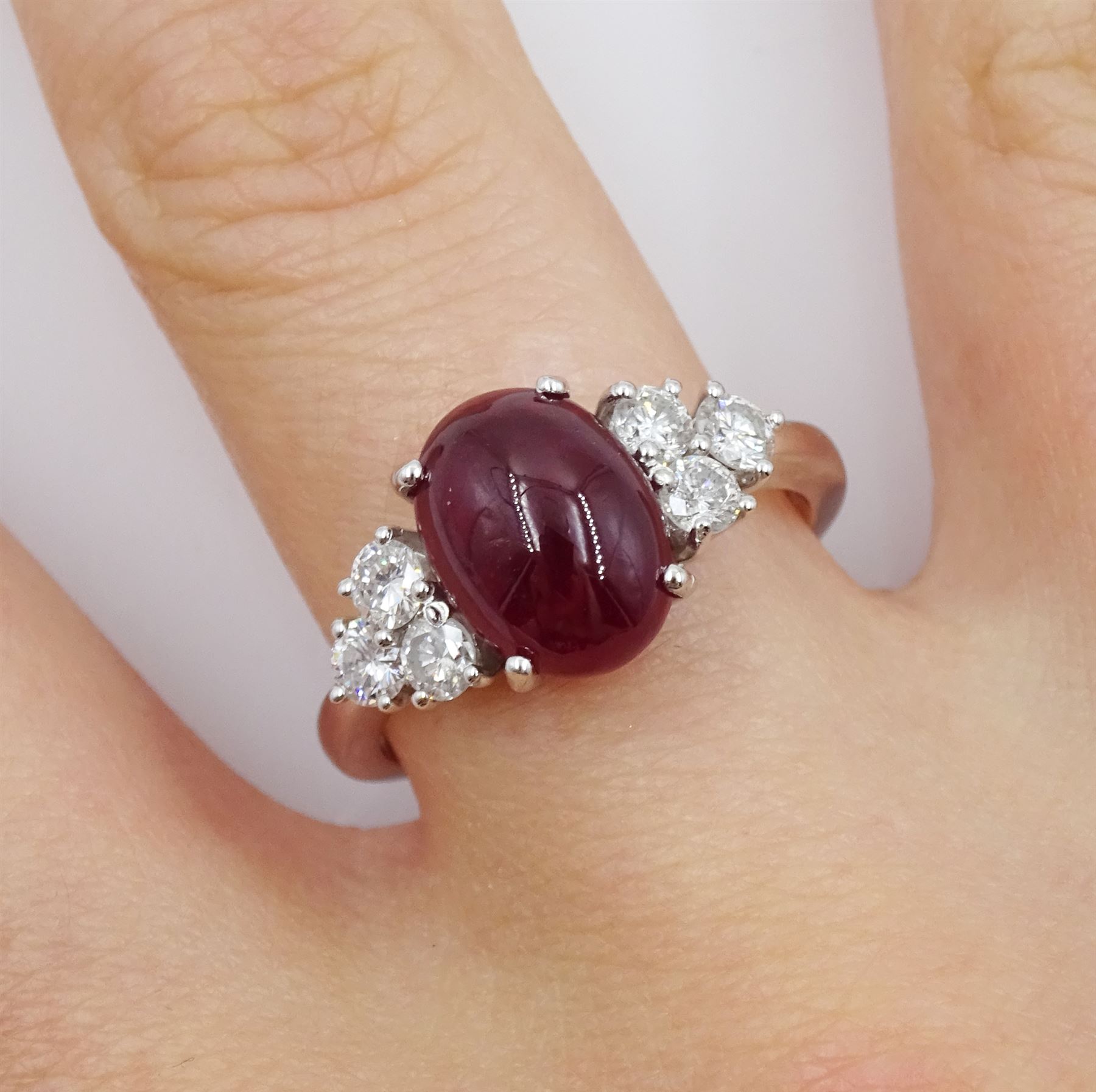 18ct white gold cabochon ruby ring, set with three round brilliant cut diamonds either side, hallmarked, ruby approx 3.20 carat, total diamond weight approx 0.55 carat