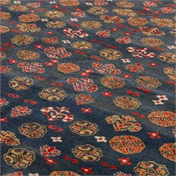 North East Persian Turkoman hand-knotted rug, deep teal blue field decorated with repeating rows of stylized octagonal guls and cruciform tribal motifs arranged in a lattice formation, enclosed composition featuring angular devices and reciprocal motifs, with cotton fringe ends