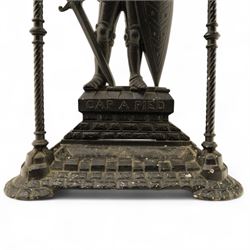 Early 20th century painted cast iron hall stand, formed as a standing armoured figure with red and yellow feathered crest, twin rails and integral drip tray with castellated edge