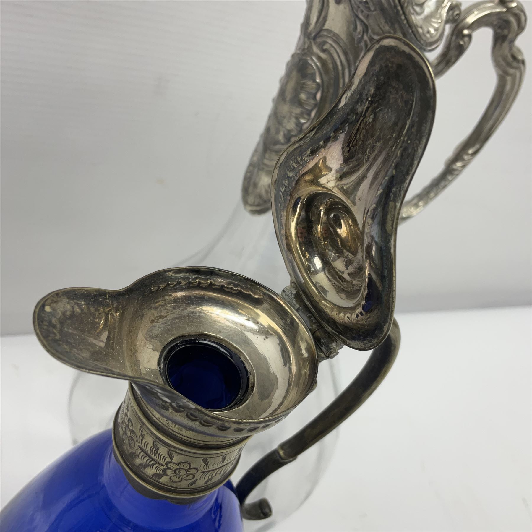 Silver plate mounted blue glass claret jug of ovid form, with C scroll handle, together with two other silver plate mounted claret jug