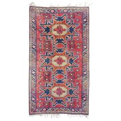 Caucasian pale red ground rug, the field decorated with three large medallions and stylised flower heads, within repeating border 