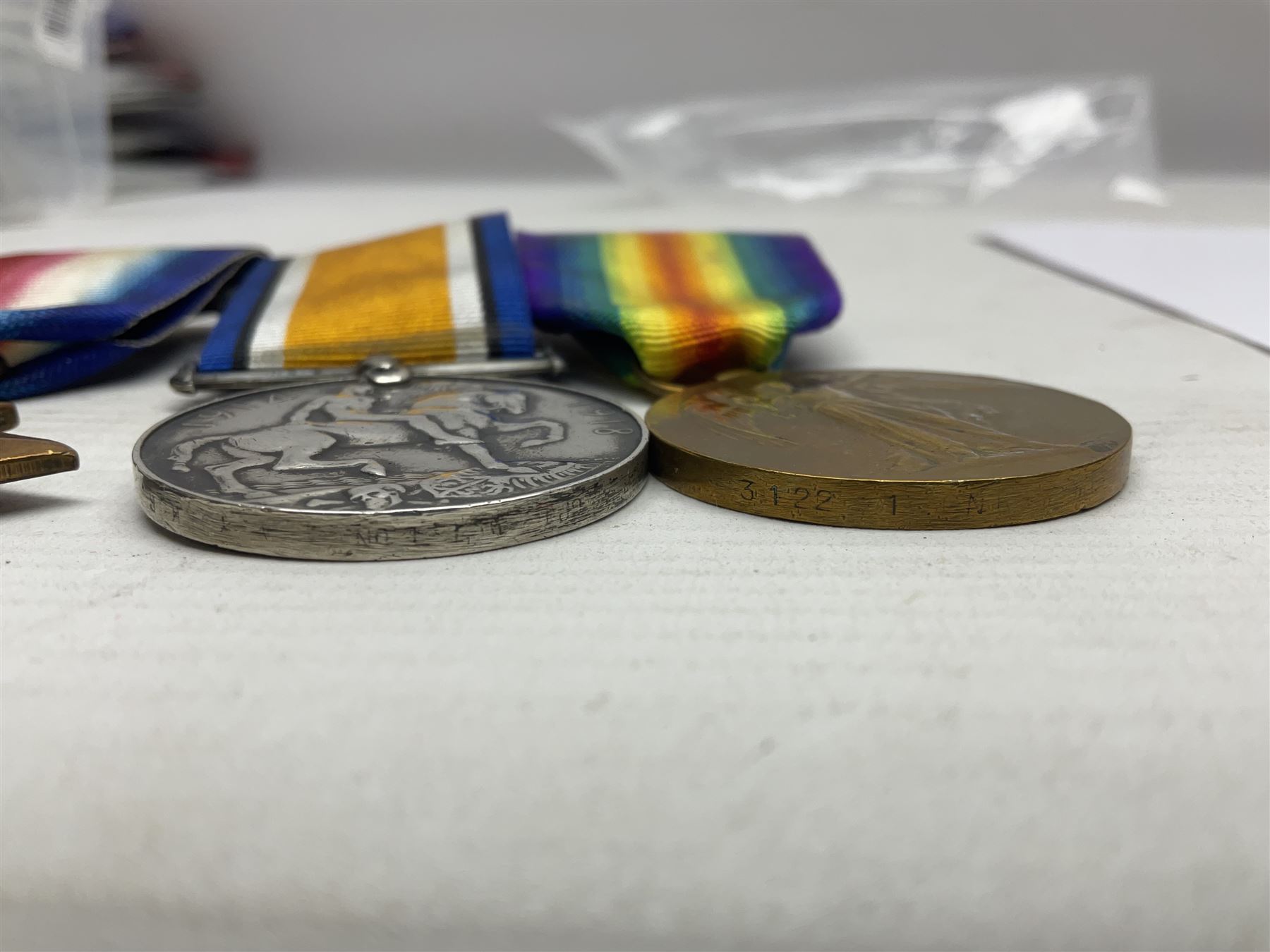 Made-up group of three WWI medals comprising 1914 Star awarded to 23598 Gnr. F. Jefferson R.G.A., British War Medal and Victory Medal with names removed; with ribbons on wearing bar; 1942 Motorist's Medal and small quantity of cap badges, Royalty badges etc