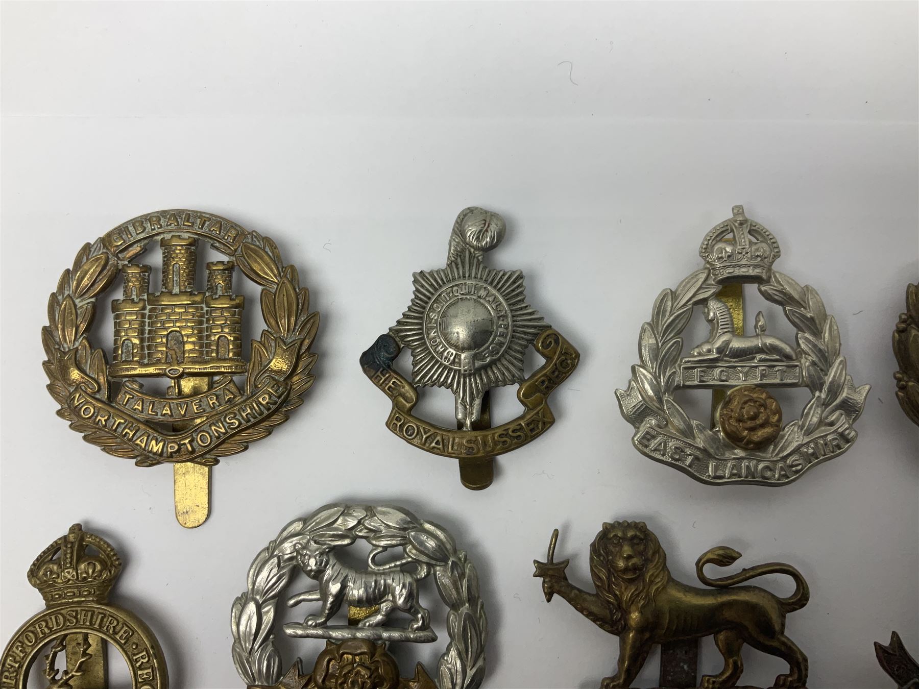Twenty cap badges including Hertfordshire, Royal Sussex, Cambridgeshire, Hampshire, Notts and Derby, East Surrey, Herefordshire, South Lancashire, Devonshire, Bedfordshire, Durham Light Infantry etc (20)