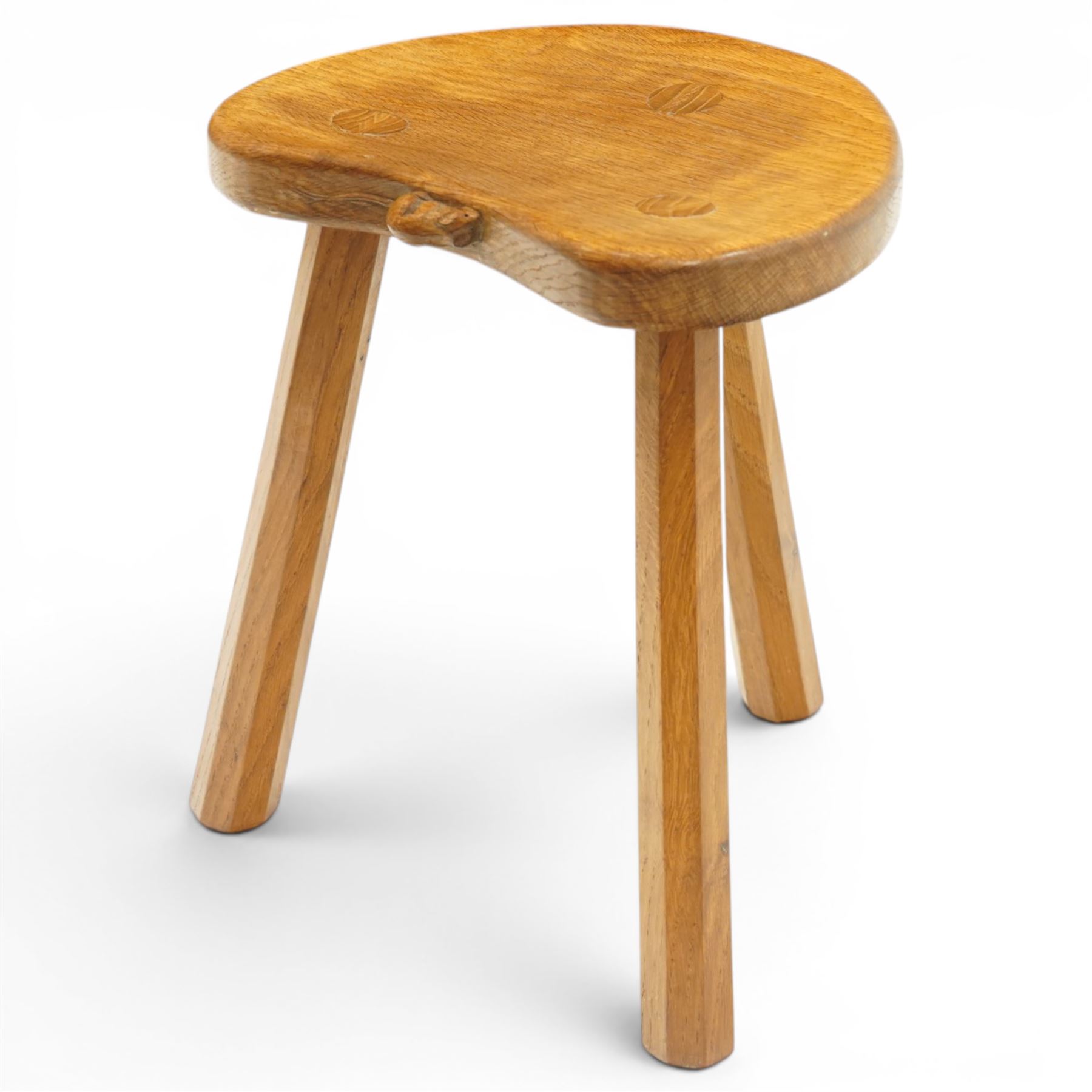 Mouseman - oak three-legged milking stool, dished kidney-shaped seat, raised on three octagonal splayed supports, with carved mouse signature, by the workshop of Robert Thompson of Kilburn