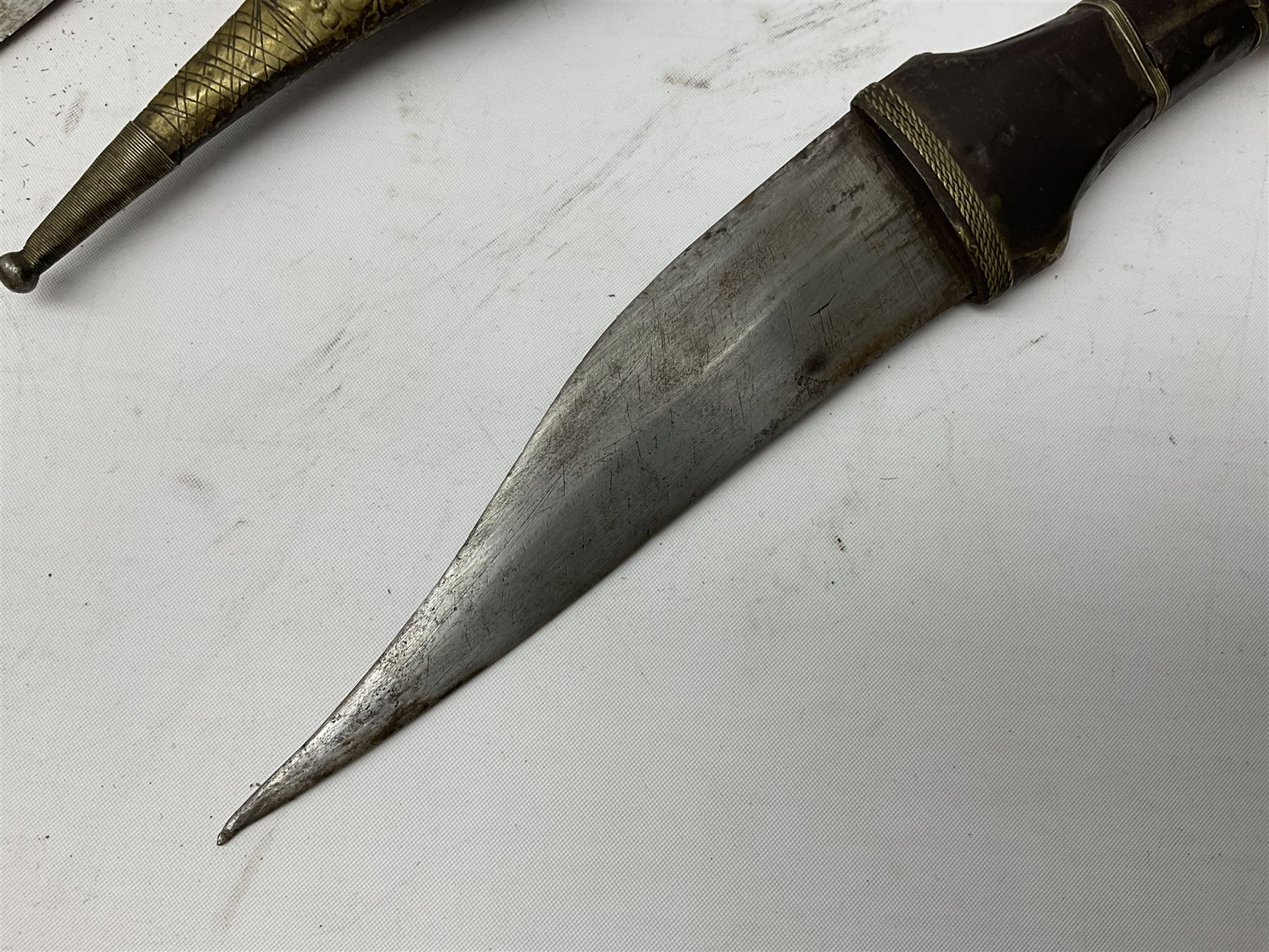 Near pair of African Moroccan Berber tribal Shula daggers each with engraved 39cm curving fullered steel blade, carved and inlaid horn grip and leather covered scabbard L57cm overall; kindjal style dagger with brass covered and jewelled grip and scabbard; another Eastern dagger with leather covered grip and scabbard; and a large Eastern knife with animal hide scabbard (5)