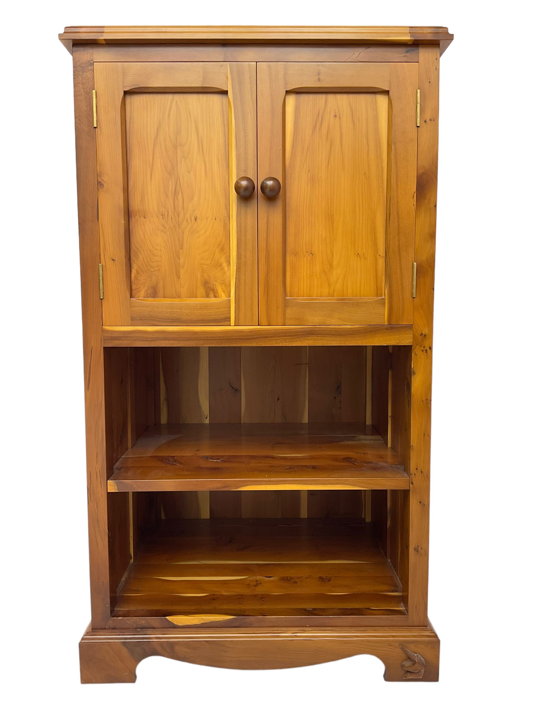 Unicornman - yew wood cabinet, moulded hinged lid over two panelled doors and shelves (W56cm, H99cm, D45cm); and four Unicorn man CD racks two in yew wood and two in oak (W20cm, H36cm, D20cm); all carved with unicorn signature and by Geoff Gell, Coxwold
