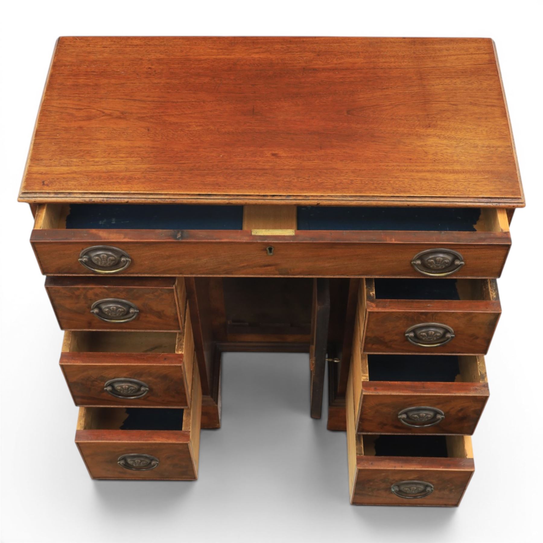 Early 20th century Georgian design figured walnut kneehole desk, rectangular moulded top over one long frieze drawer, kneehole recess with cupboard and drawer above, flanked by six short drawers with oval pressed brass handle plates, moulded plinth base on bracket feet