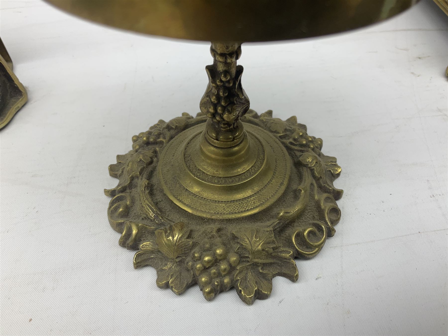 Collection of victorian and later brass desk accessories, to include a letter holder with cherub design, ink well of square form with hinged lid, brass table bell, brass casket with relief decoration, etc  