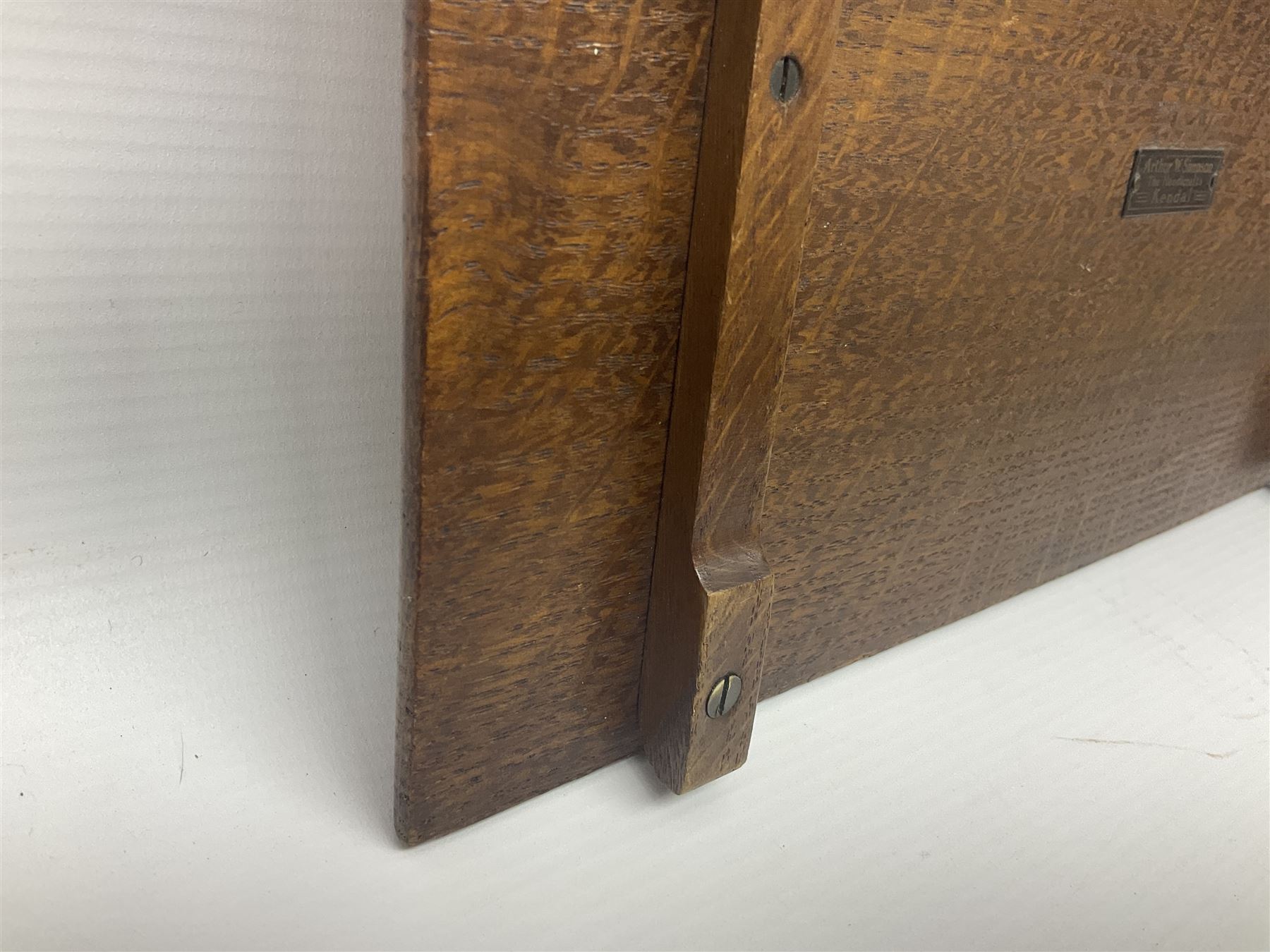 Arts and Crafts oak stand by Arthur Simpson of Kendal, of rectangular form with central hammered pewter panel, surrounded by a border with carved foliate corners, upon two bar supports, bearing label detailed 