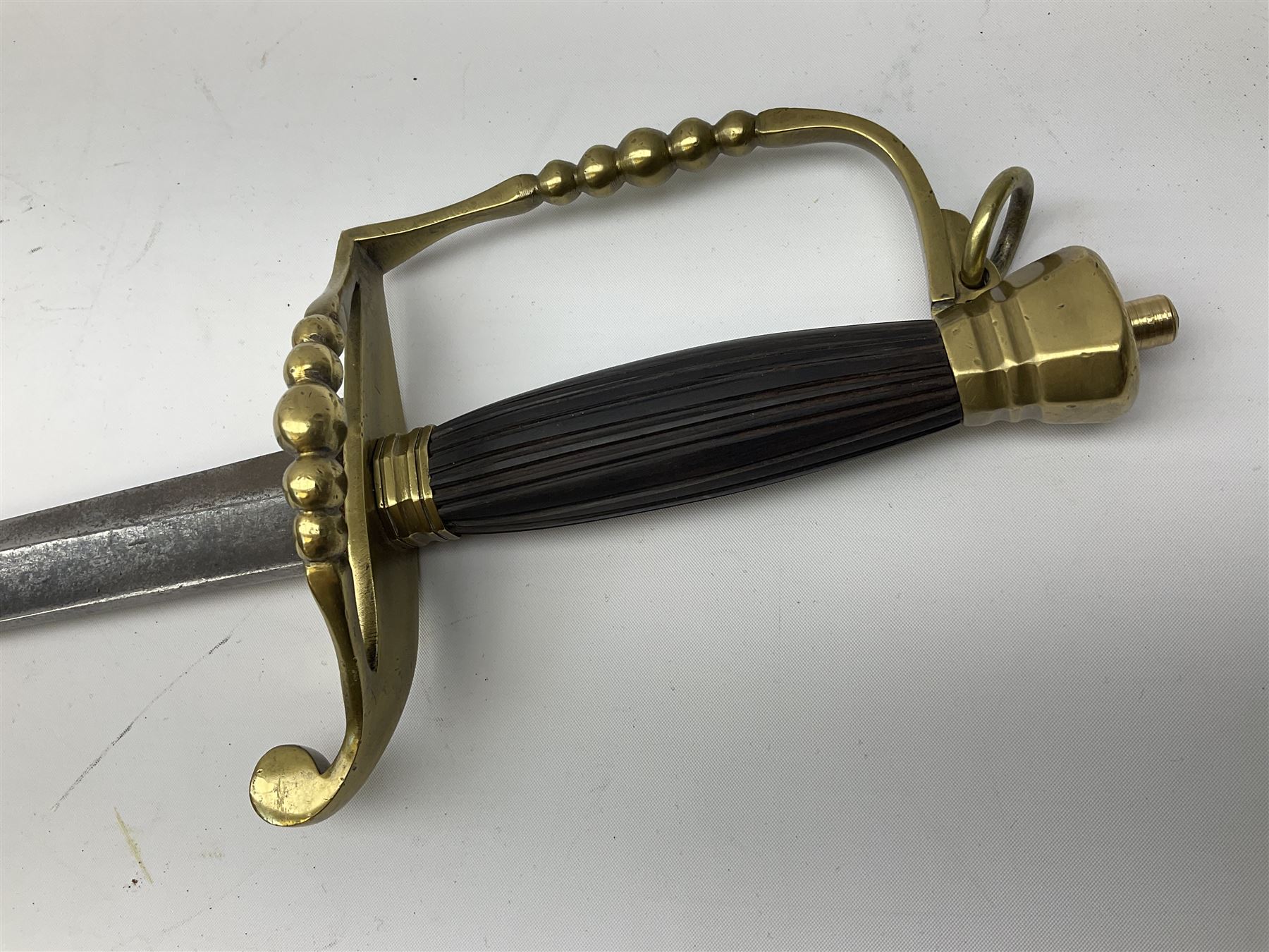 Five-ball spadroon sword with 78.5cm fullered steel blade and brass hilt with fluted swollen grip; in brass mounted leather scabbard, the locket with traces of the makers name John Knubley 11 Charing Cross L97.5cm overall