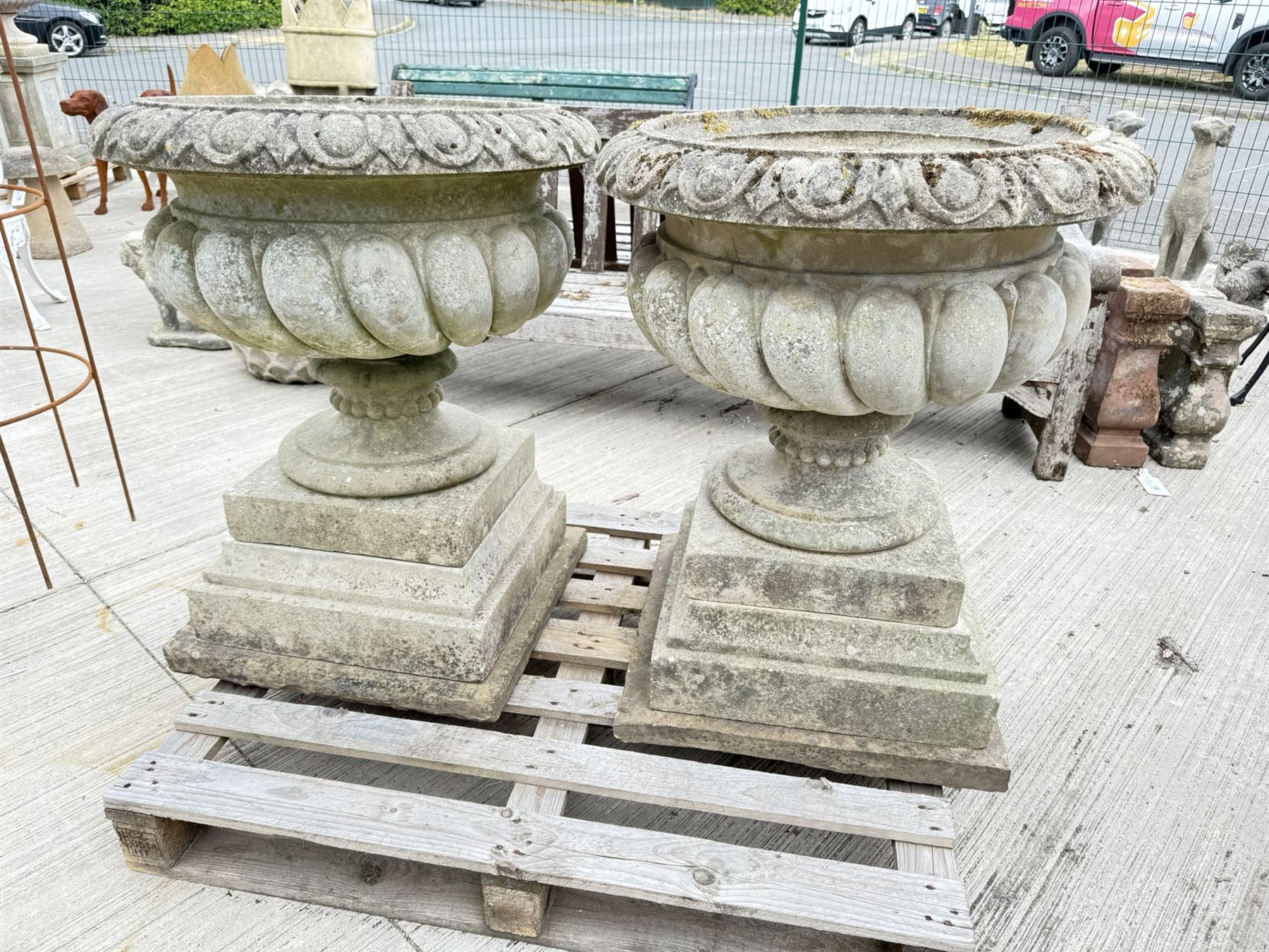 Pair of large weathered Country House Haddonstone garden urns, acanthus carved rim above gadrooned bowl, beaded detailing to the neck, raised on stepped double plinth base
