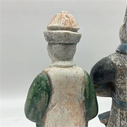 Three Chinese terracotta court attendant tomb figures, probably Ming Dynasty, two examples decorated in Sancai green glaze, the third example decorated in two tone blue glaze, each upon stepped square bases, tallest H22.7cm