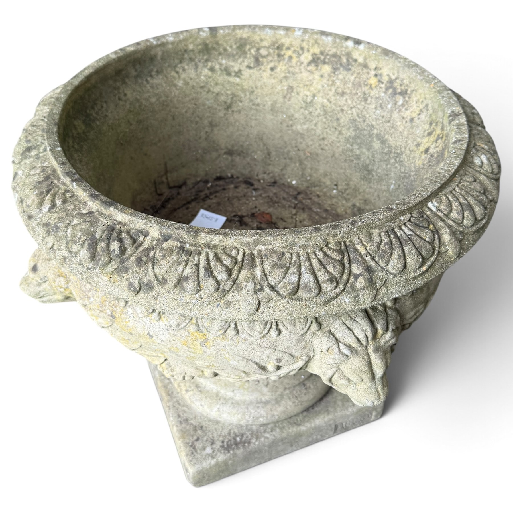 Regency design weathered cast stone garden urn of kylix form, the anthemion and arrowhead moulded everted rim over a fruiting laurel and lion-mask relief decorated body, waisted socle on square base, stamped HGC