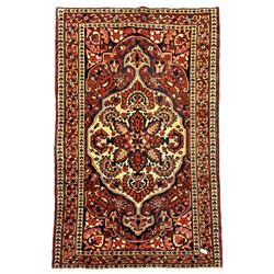 Central Persian Bakhtiari rug, red ground field decorated with overall floral design, triple band border decorated with repeating flower head and plant motifs 