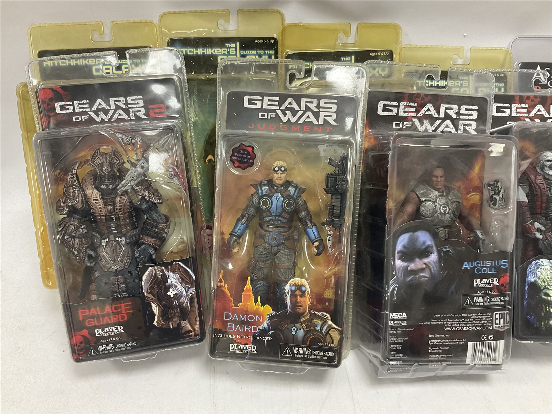 Sixteen carded action figures comprising seven 'Gears of War'; four 'Hitchhikers Guide to the Galaxy'; two 'Torchwood'; 'Planet of the Apes'; 'Bruce Lee'; and 'Assassin's Creed'; all in unopened packs (16)