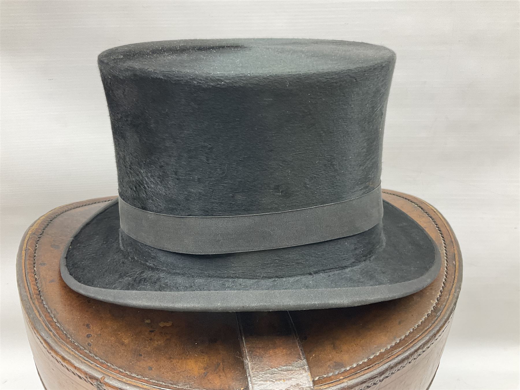 Early 20th century black silk top hat by Woodrow of Manchester and London, with manufacturer's stamp to the silk lined interior, housed in fitted tan leather hat box with removable internal compartments with straps, brass escutcheon and engraved plaque, hat internal measurements approx 20cm x 15cm