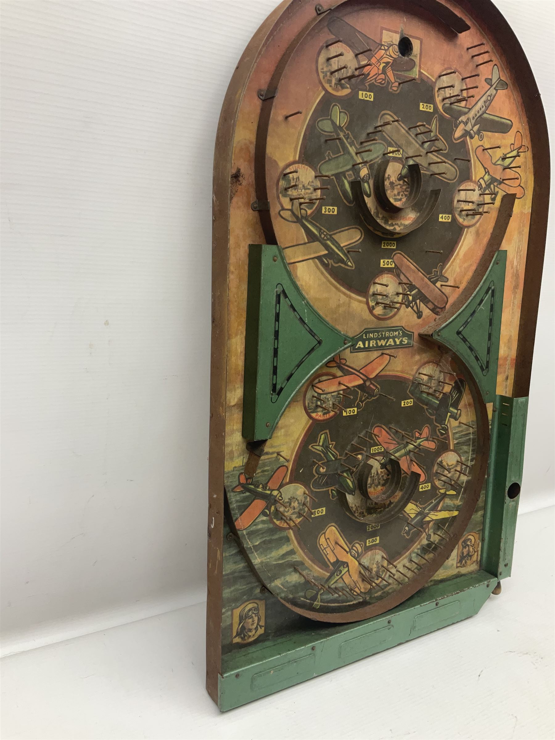 1934 Lindstrom's 'Airways' tin-plate bagatelle game by Lindstrom Tool and Toy Company Bridgeport Conn., the decorative bagatelle board depicting Lindstrom's epic airway routes; with wooden peg and quantity of balls H61cm