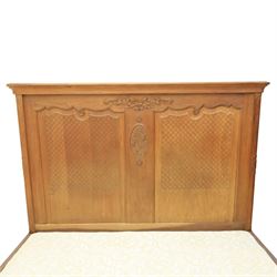 Early 20th century French oak double bedstead, the shaped and moulded headboard carved with central floral cartouche and scrolling foliage above lattice carved panels, the conforming footboard with pierced and carved decoration, shaped apron with foliate carving, raised upon cabriole supports