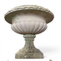 Pair of weathered cast stone Neoclassical design garden Kylix shape urns, foliate moulded rim over a gadrooned underbelly, the scalloped socle over a rectangular pedestal with faux-panelled sides, stamped with stylised ‘H’ monogram