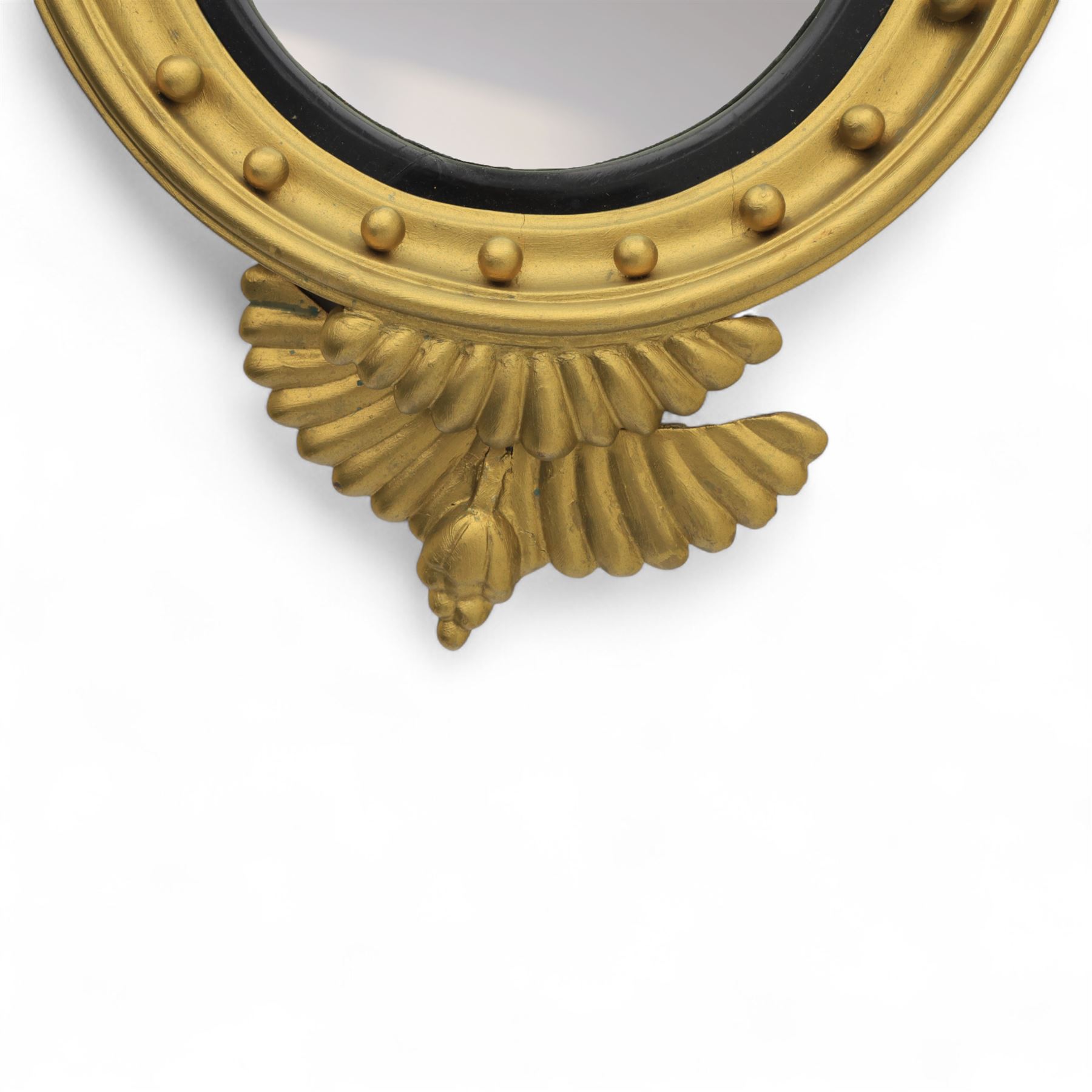 Early 20th-century Regency-style giltwood convex mirror, circular plate within a ball-mounted frame surmounted by an eagle cresting and flanked with scrolls, apron carved with foliate decoration 