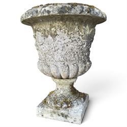 Set of four weathered composite stone urns of campana form, the everted leaf-moulded rolled rim over a body decorated with scrolling fruiting grapevines in relief, over a gadrooned underbelly and waisted socle, lobed collar on square base
