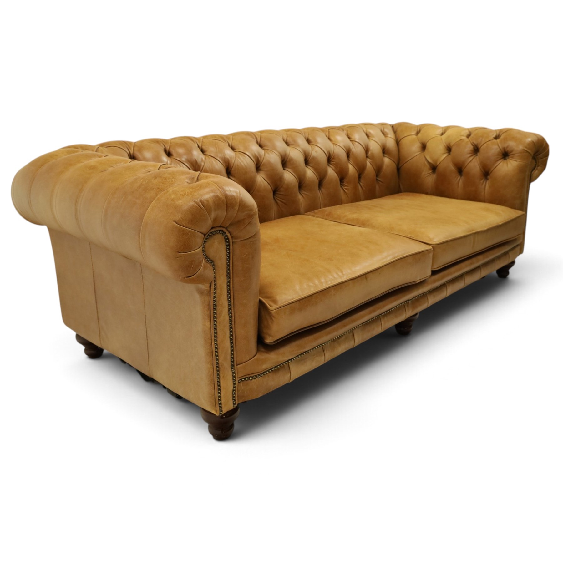 Distinctive Chesterfields - traditional shape four seater Chesterfield sofa, the rolled back and arms upholstered in deep-buttoned tan leather with matching loose seat cushions, raised on six turned supprorts