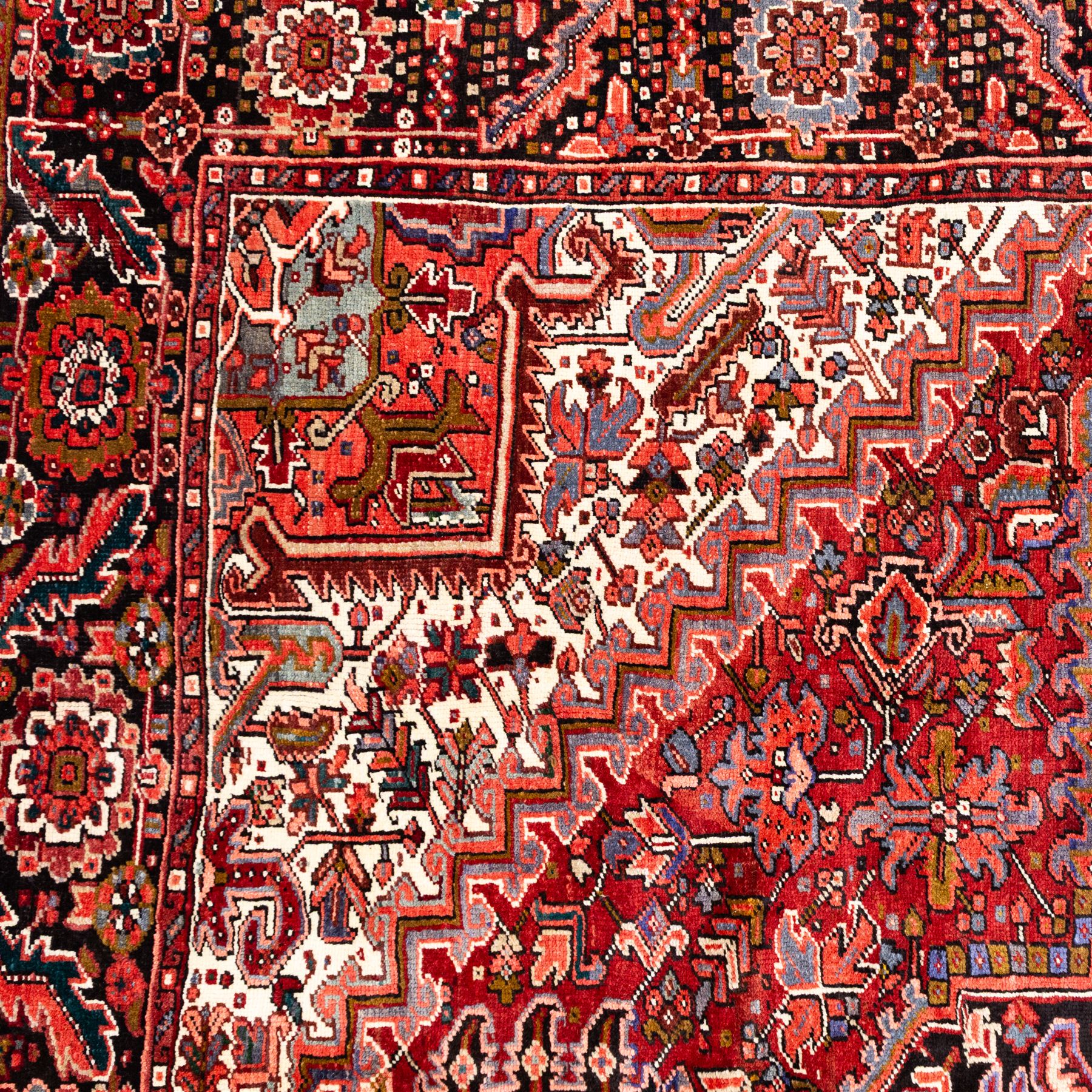 North West Persian Heriz hand-knotted carpet, brick red field, with large central angular star medallion with stepped outlines, surrounded by geometric floral devices and stylized rosettes, with corresponding corner spandrels, enclosed by a bold geometric main border with multiple guard stripes, with cotton fringe ends 