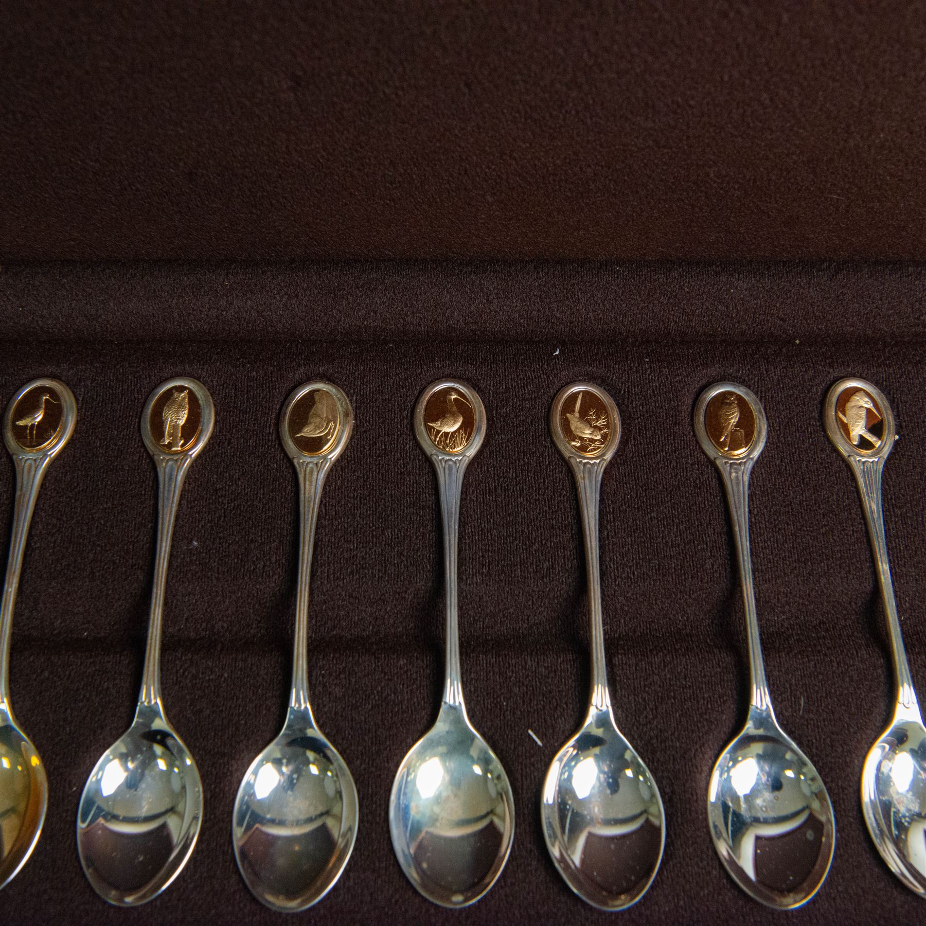 Royal Society for The Protection of Birds silver spoon collection, twelve spoons each inset with a silver-gilt bird cameo, hallmarked John Pinches Ltd, London 1975, in wooden presentation case with certificate of authenticity
