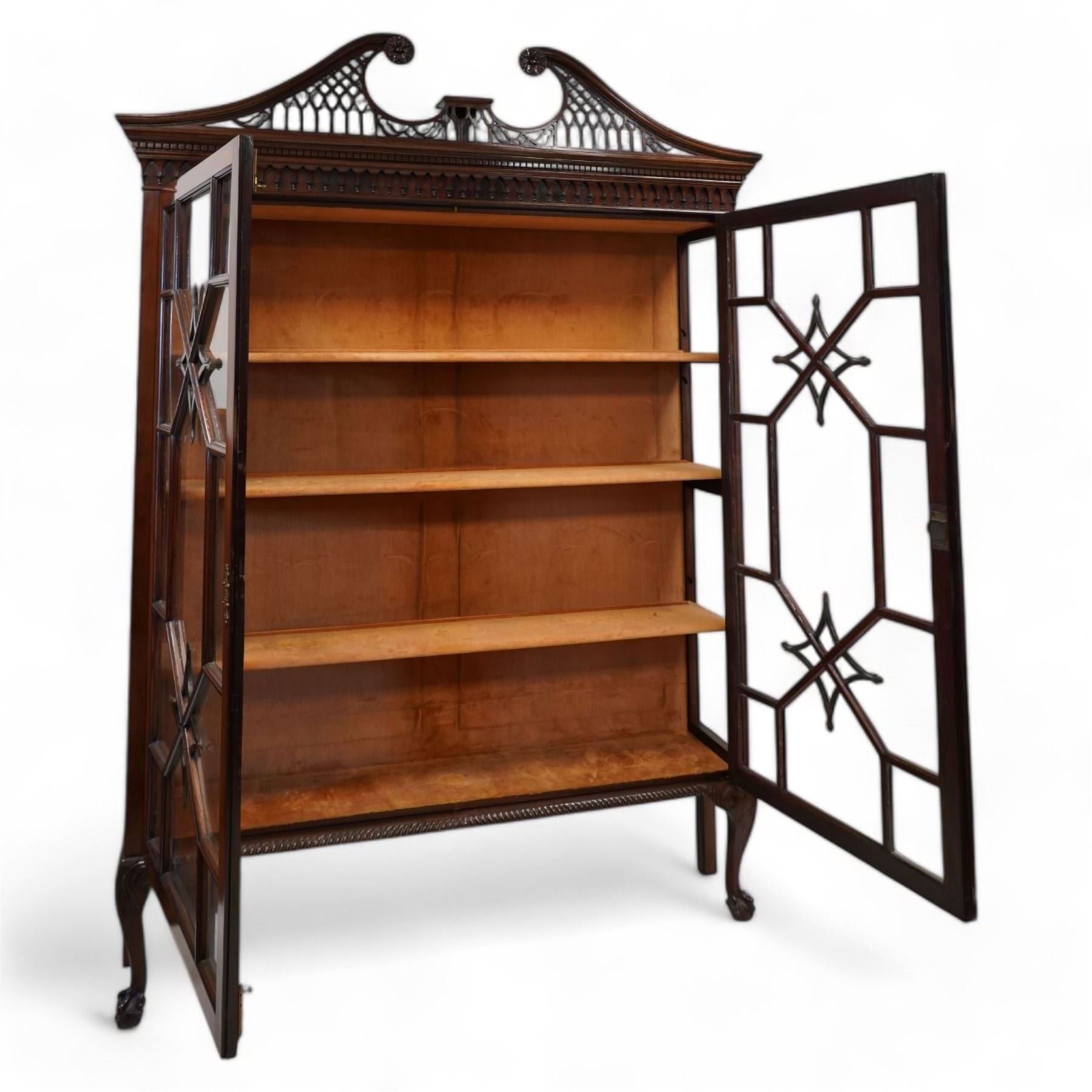 Large George III mahogany bookcase display cabinet, pierced swan neck pediment with floral head roundels over dentil and arcade frieze, enclosed by two geometric astragal glazed doors with lozenge motifs, the lined interior fitted with three shelves, gadrooned lower rail over acanthus carved cabriole supports with ball and claw feet 
