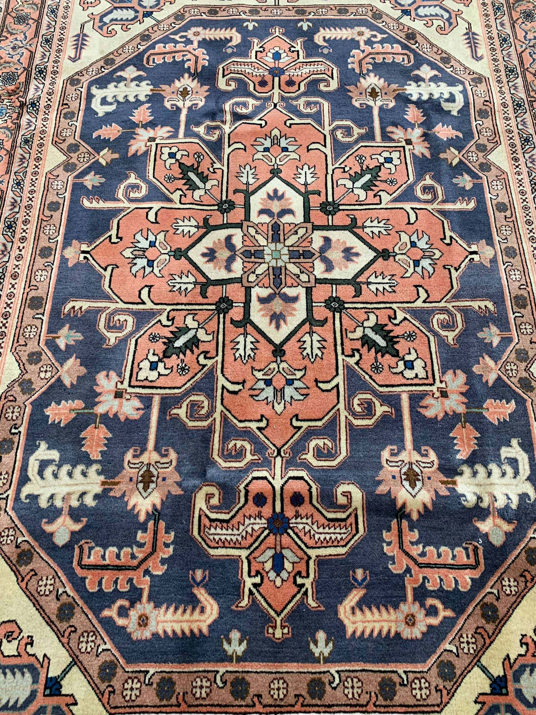 Persian ivory and peach ground, overall geometric design, the field with central star medallion surround stylised leaf motifs, guarded geometric design border