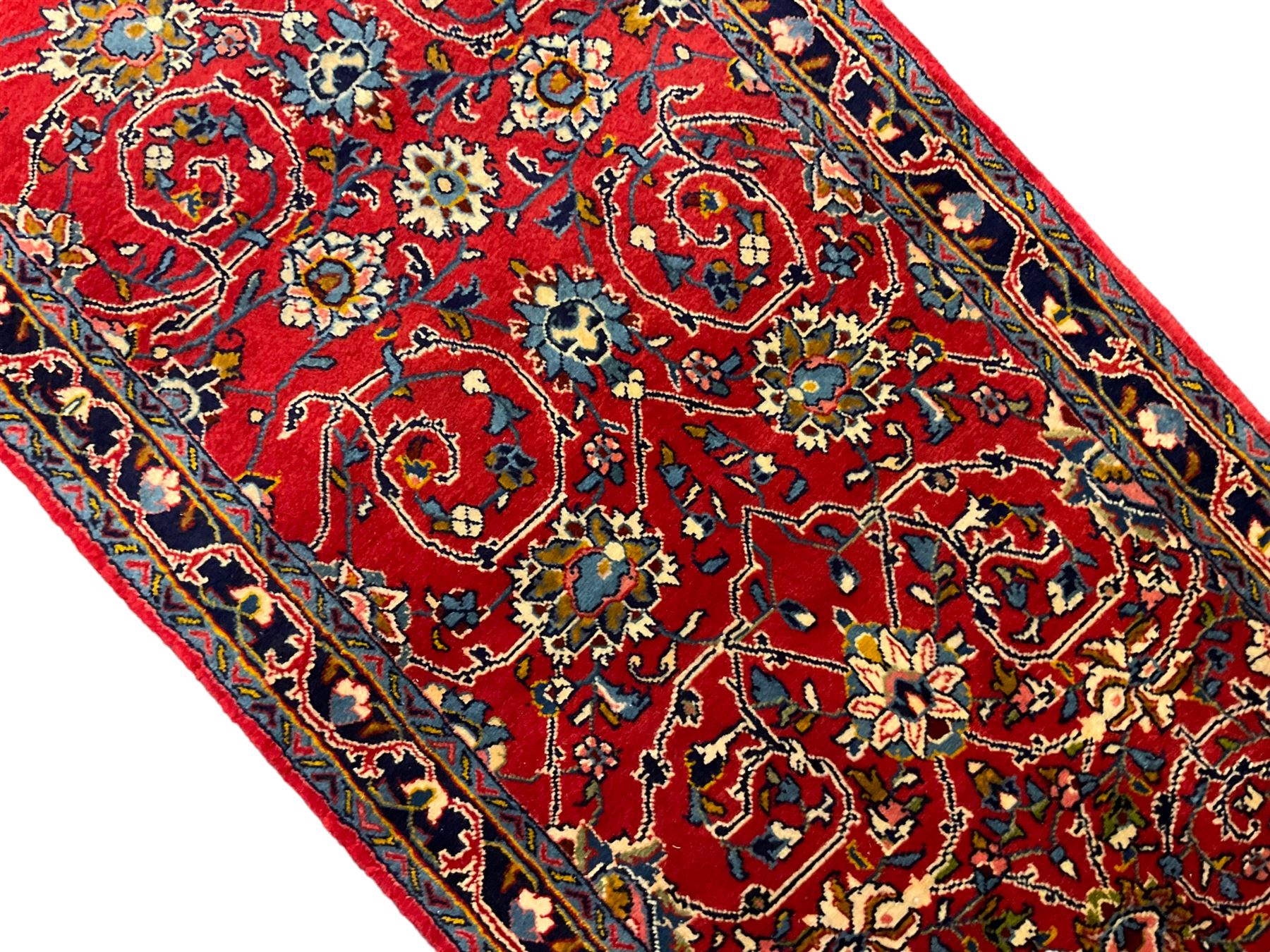 Central Persian Kashan crimson ground runner rug, the field decorated with interlacing branch and stylised flower head motifs, the guarded indigo border with repeating trailing foliate patterns