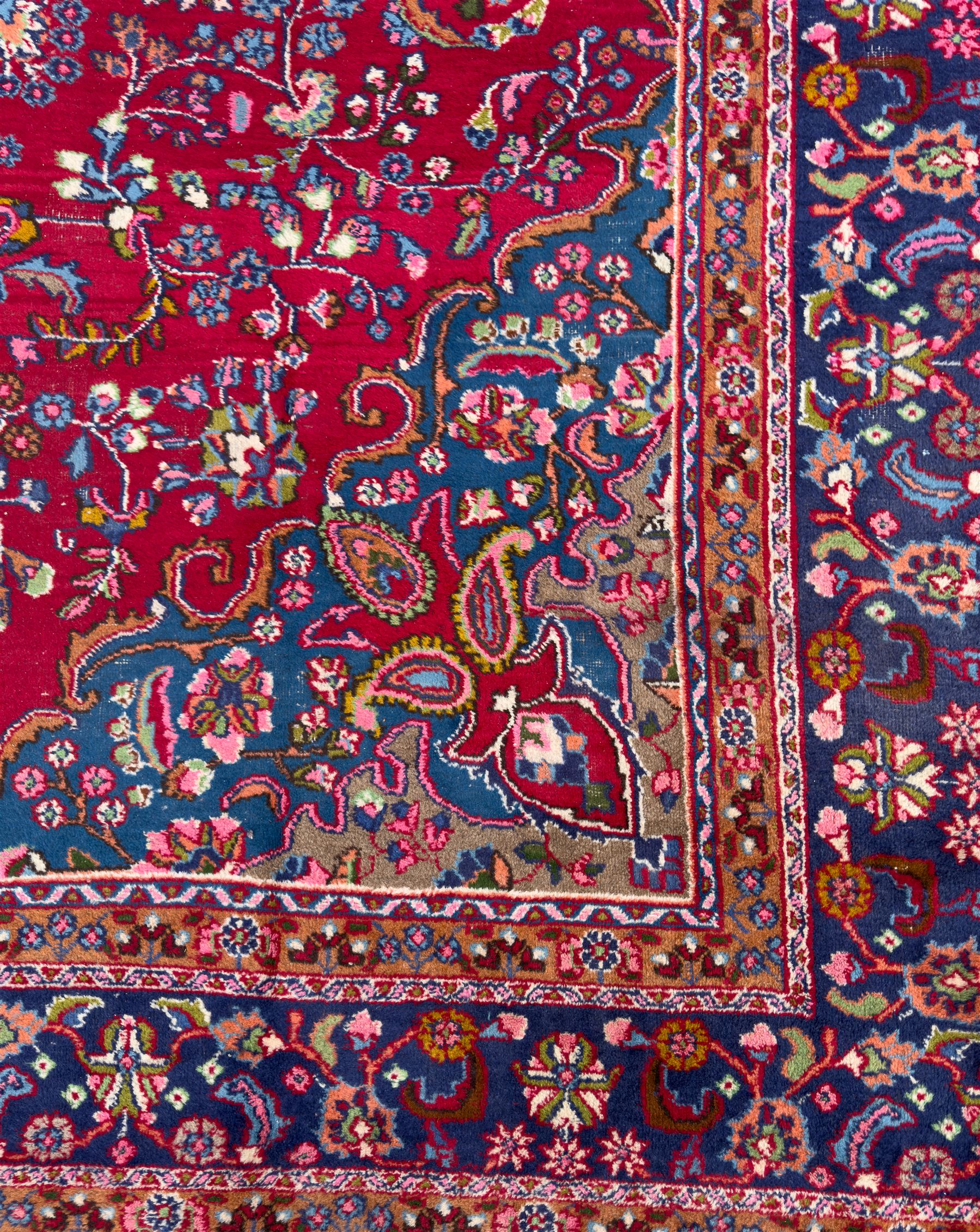 Pair of Persian wool rugs, each with rich red ground, one centred with a diamond-shaped medallion and navy spandrels within a floral field, the other with radiating floral medallion and scrolling foliate motifs, both enclosed by multiple borders with palmette and flowerhead designs, from the region of Kashan 291x376, 299 x 378 