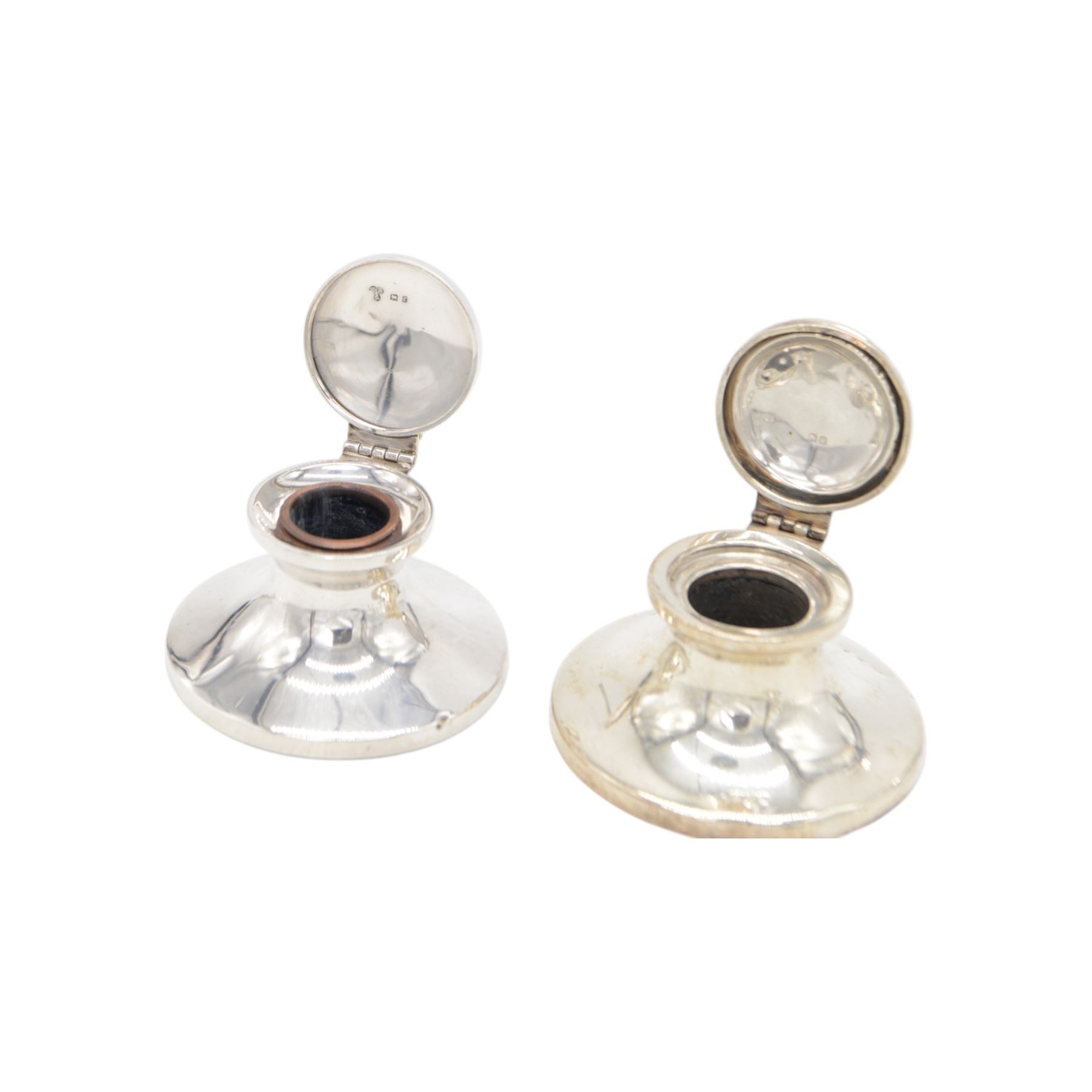 Four early 20th century silver mounted capstan inkwells, all of typical circular form with hinged covers, all hallmarked 