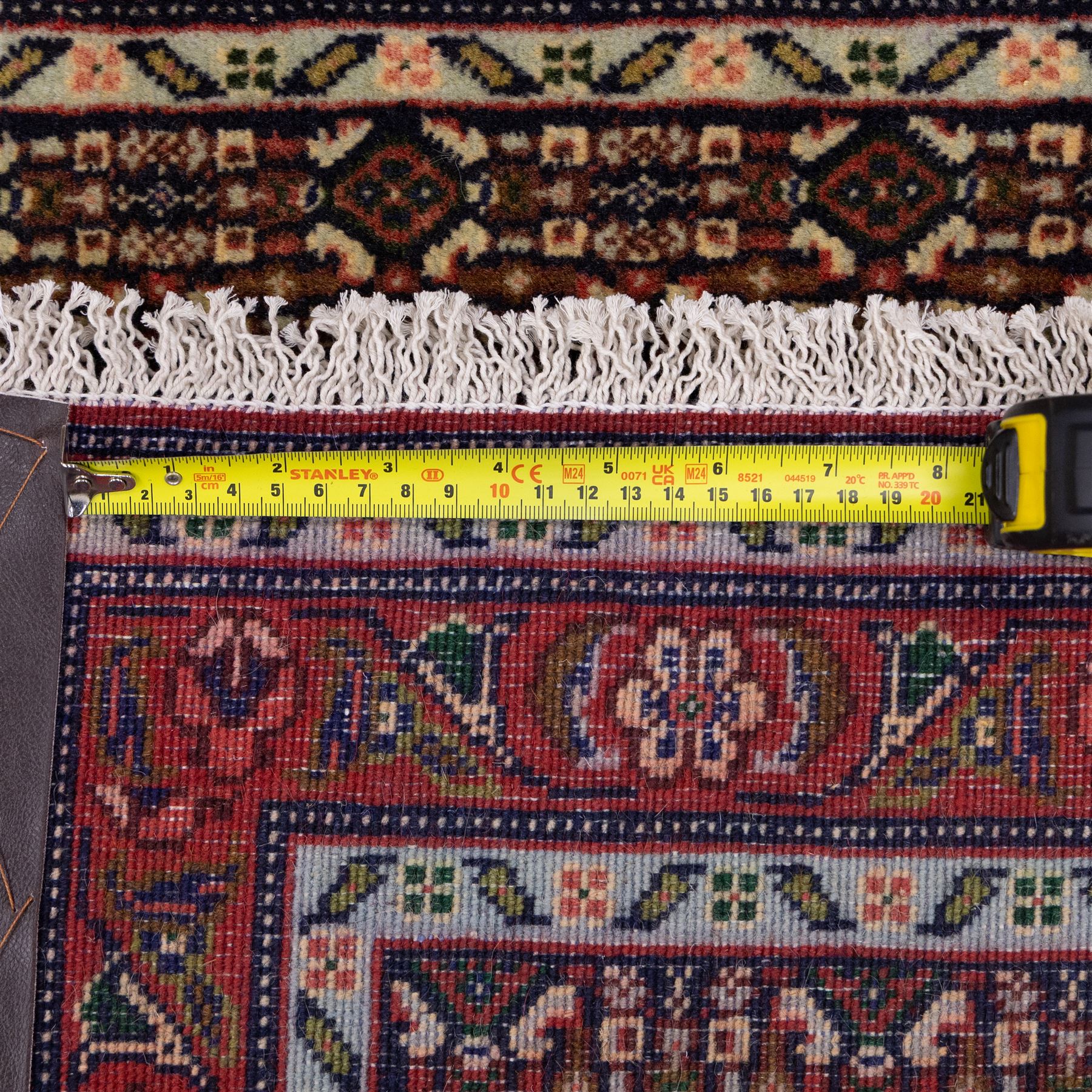 North West Persian Senneh hand-knotted runner, decorated with a continuous series of stepped and hooked geometric medallions against a madder red ground, enclosing herati style and small geometric floral motifs, framed by a principal border and flanked by multiple narrow guard stripes, with cotton fringe ends 