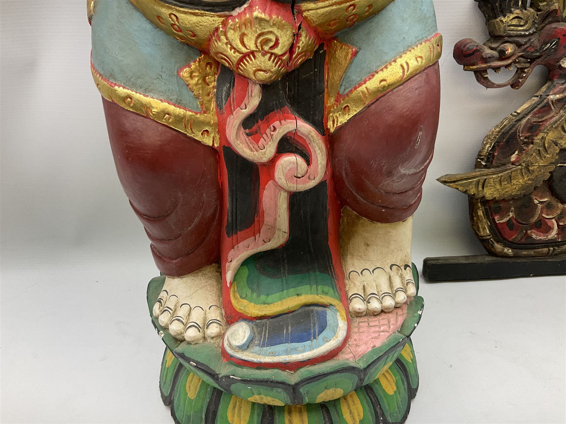 Balinese wood wall panel carved as a dragon boat with passengers, painted in reds and greens with gilding, together with a carved wood figure of Ganesh Deity decorated with gilt, raised upon circular lotus flower plinth, H78cm