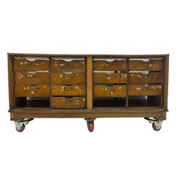 Early 20th century oak framed and glazed haberdashery / shop display cabinet, fitted with sixteen drawers (three missing), on later casters