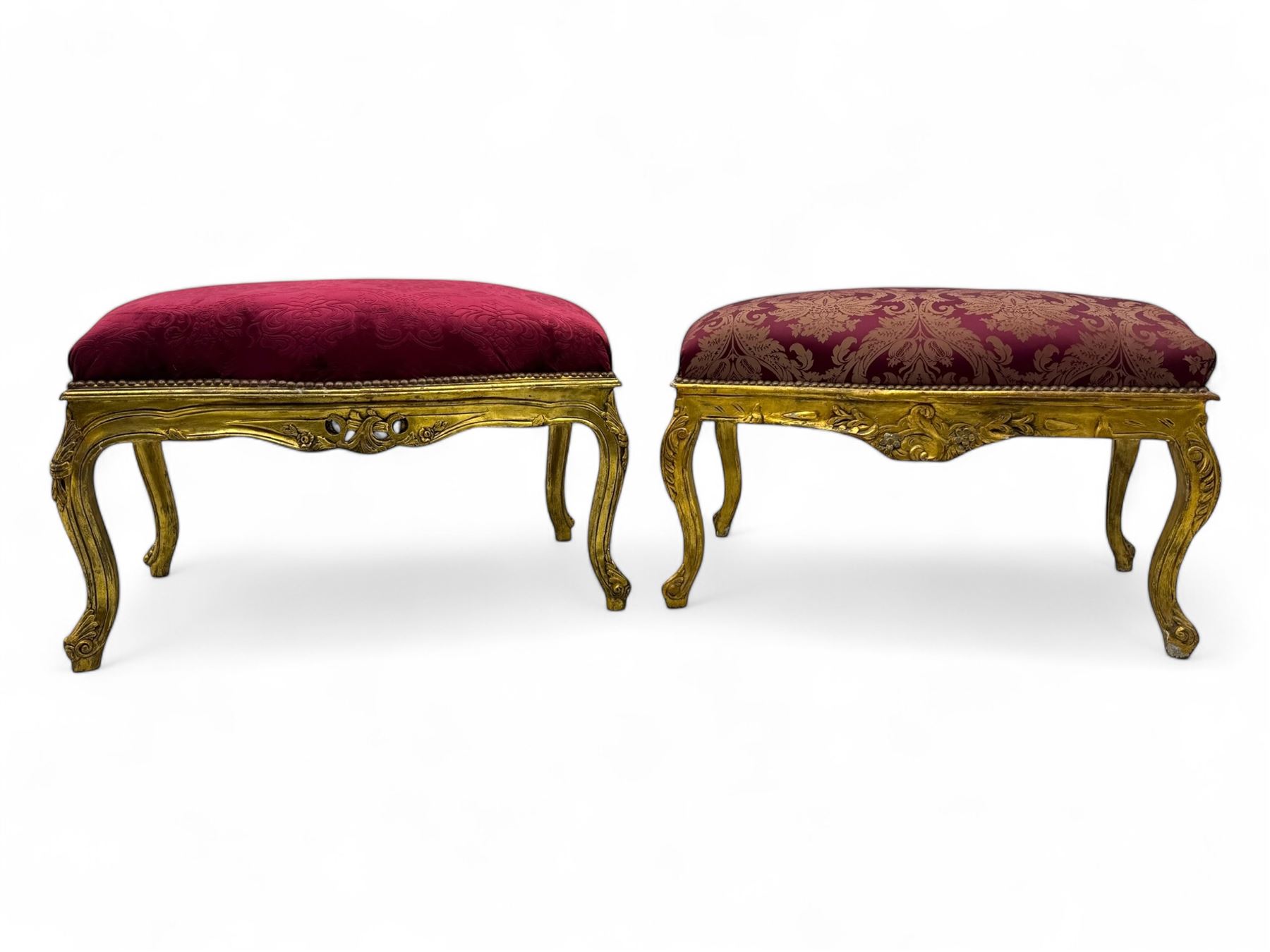 Pair of Louis XV-design giltwood stools, each upholstered in red damask fabric with slight variations in patterns, the carved frames adorned with scrolling foliage and shell motifs, raised on cabriole supports