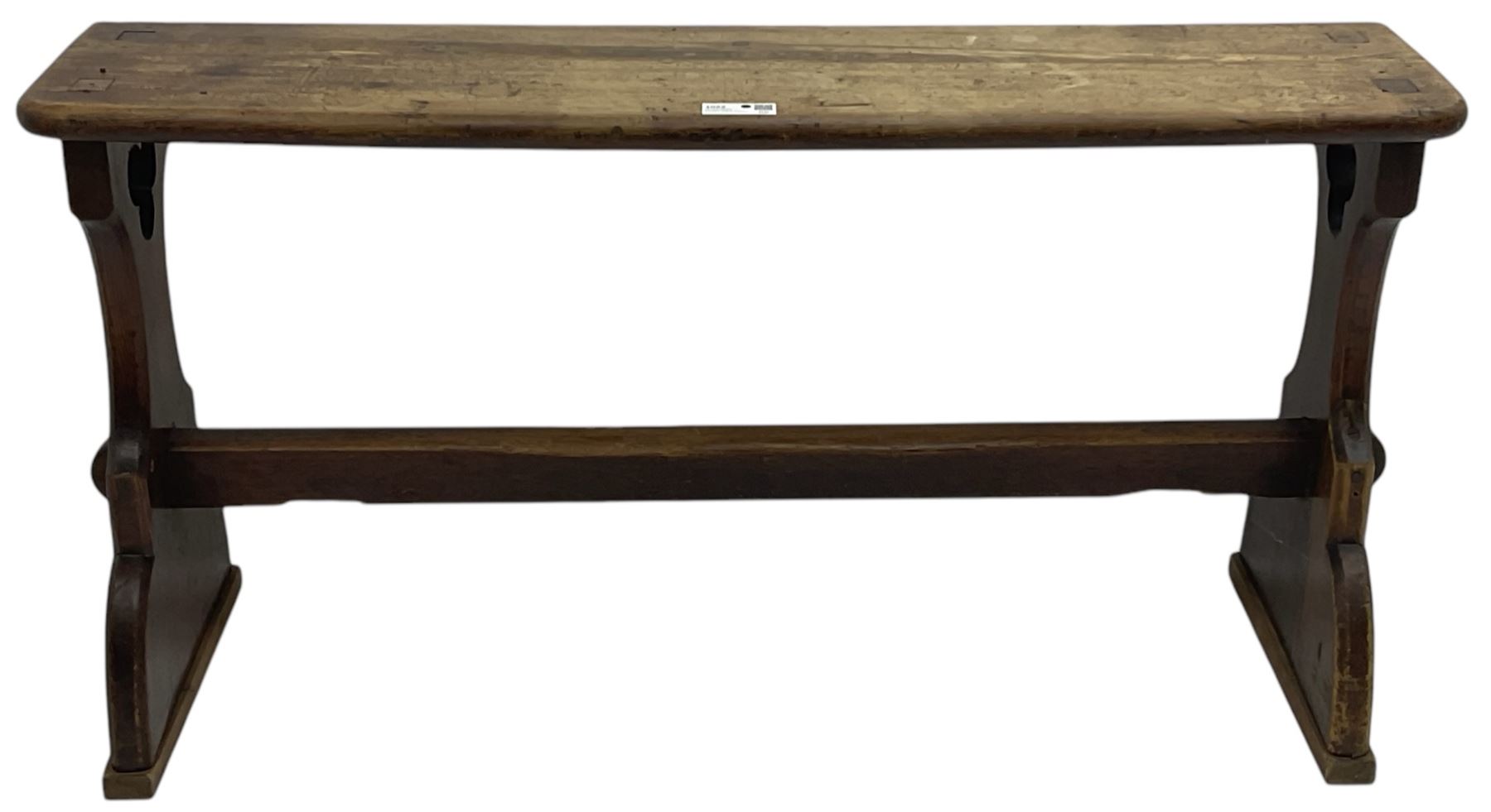 Late Victorian ecclesiastical pitch pine side table, rectangular bow-front top, on shaped end supports pierced with quatrefoils, united by pegged stretcher 