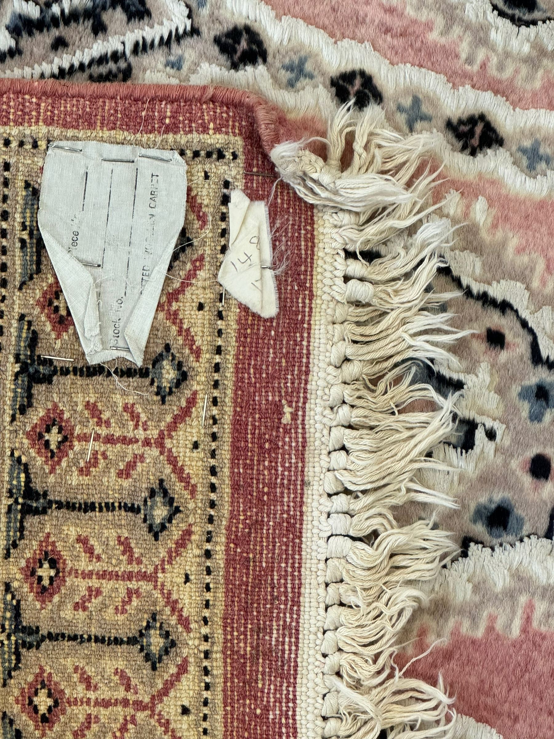 Persian design pale pink ground rug, the field divided into panels and decorated with Gul motifs, wide multi-band border with geometric patterns 