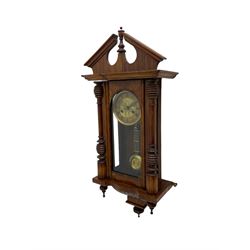 German early 20th century wall clock in a mahogany case with an architectural pediment and turned finial, with applied carving and pendant finials, fully glazed door with a visible gridiron pendulum, eight-day spring driven striking movement striking the hours on a gong, dial with Roman numerals to the chapter and a gilt repoussé centre.   


