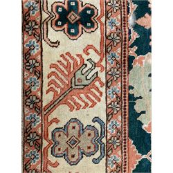 Persian emerald green ground rug, the field decorated with large stylised plant motifs, ivory ground border with repeating leaf motifs, the guards decorated with trailing branch and flowerhead motifs