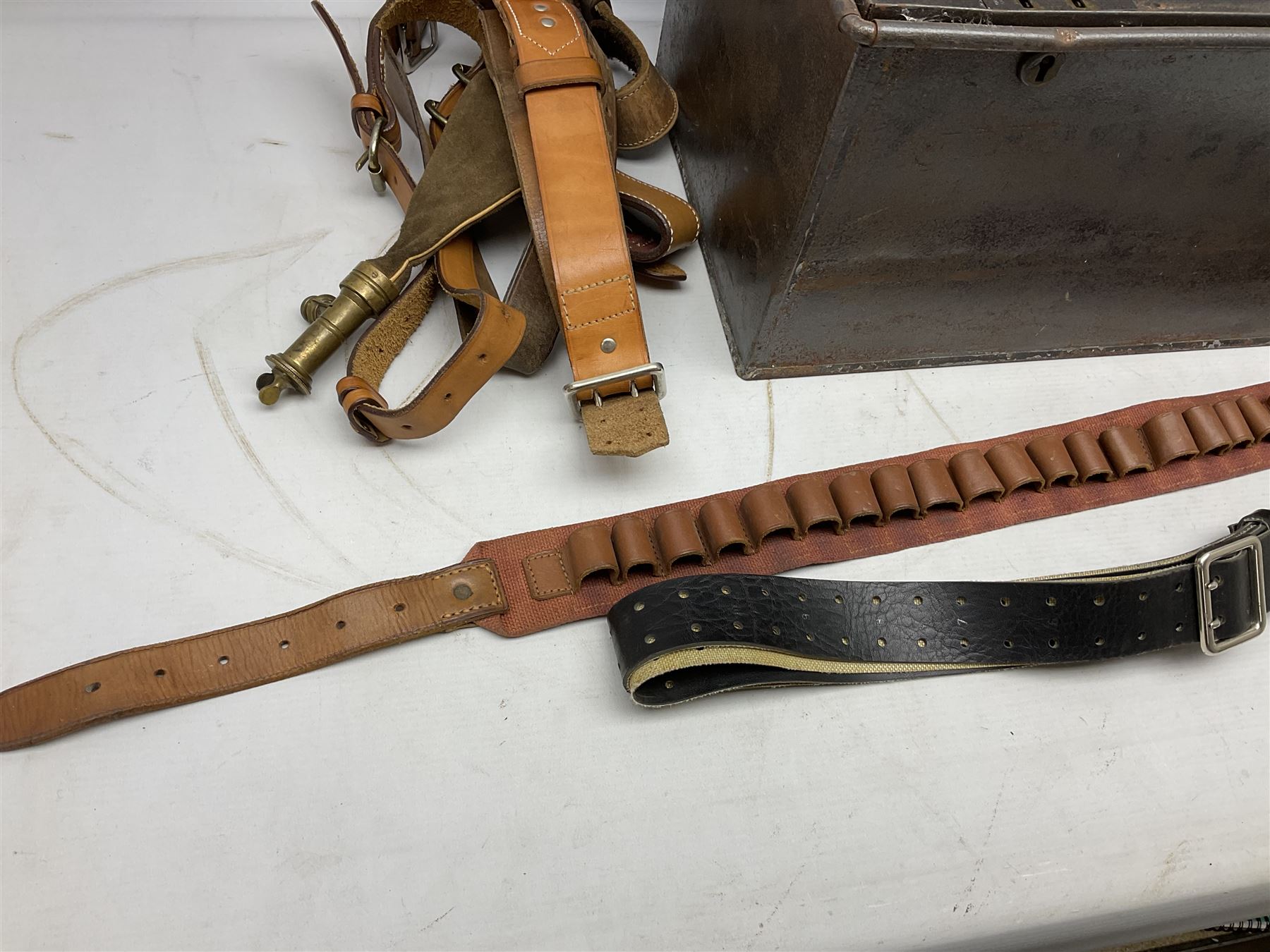 Assorted militaria including ten leather or canvas cartridge and other belts, maroon beret with 17th Lancers cap badge, modern bullet mould, leather and brass shot flask, two knives, shell cases, boomerang etc; in tin deed box