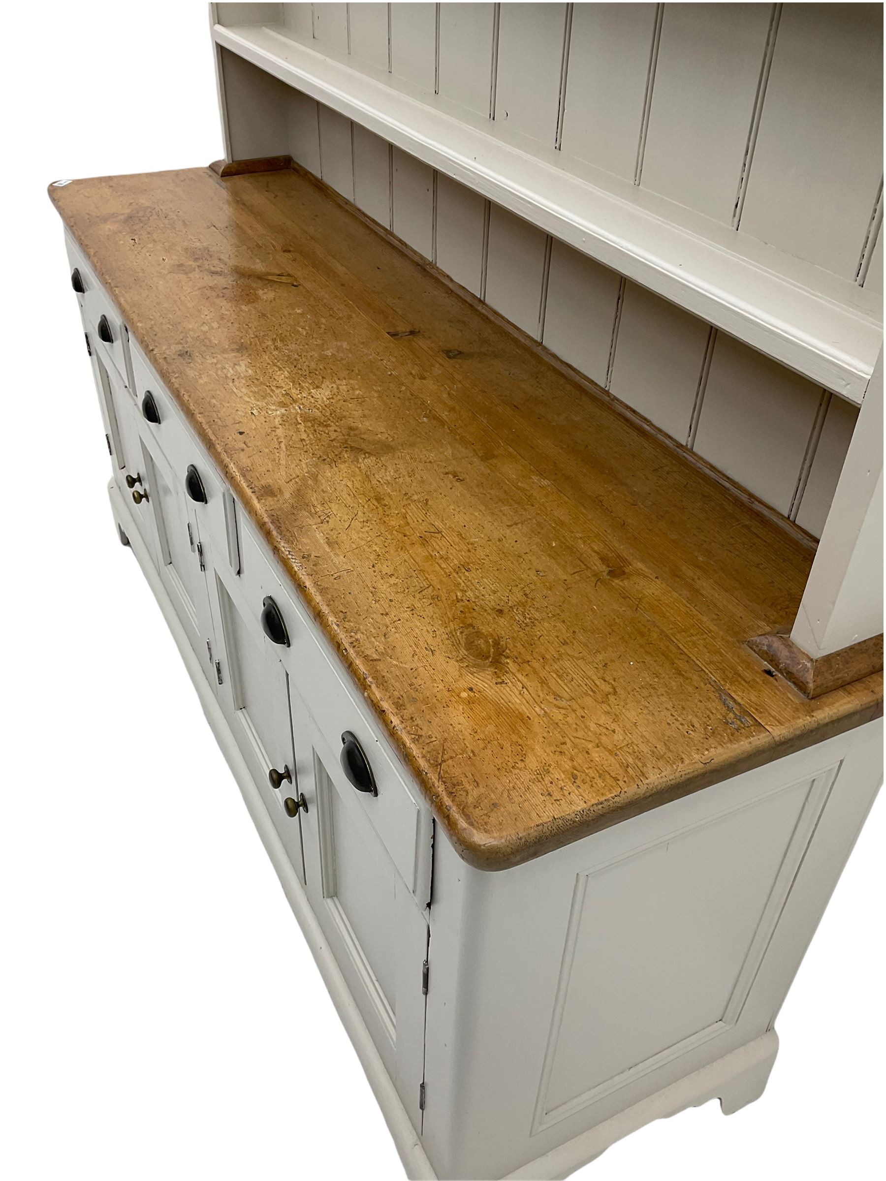 Victorian pine dresser, raised painted three heights plate rack with projecting cornice, waxed top over pained base fitted with three drawers and two double cupboards, bracket feet